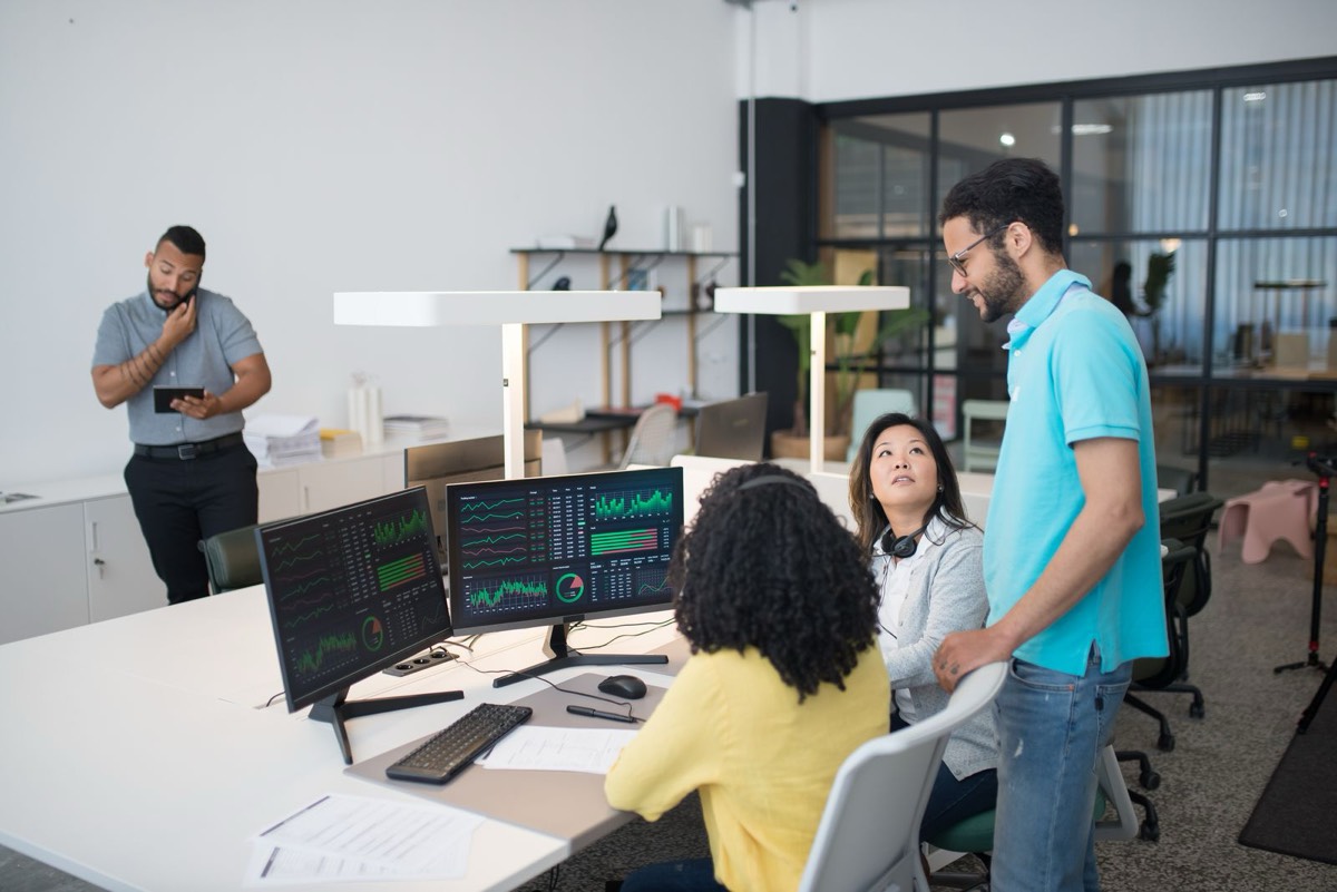 Equipo técnico revisando cuadros de mando en dos pantallas de la oficina