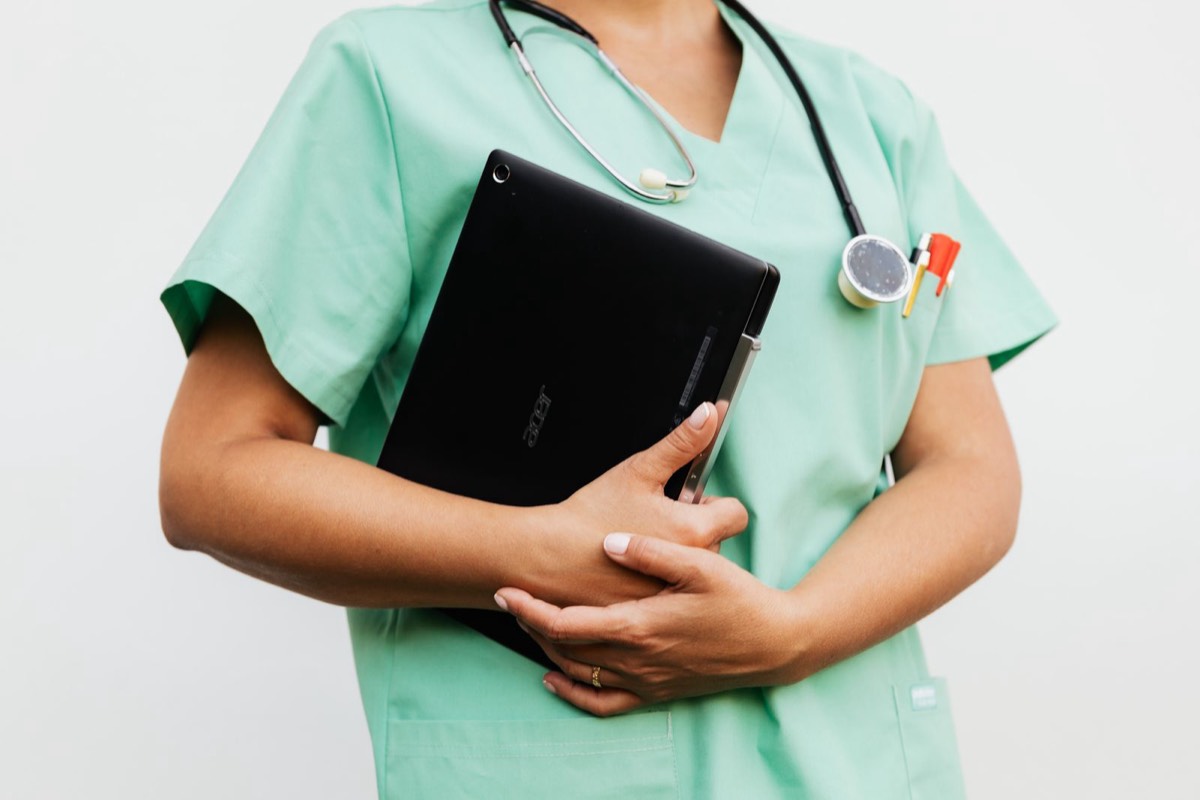 Profesional sanitaria con uniforme y fonendoscopio sujetando una tableta